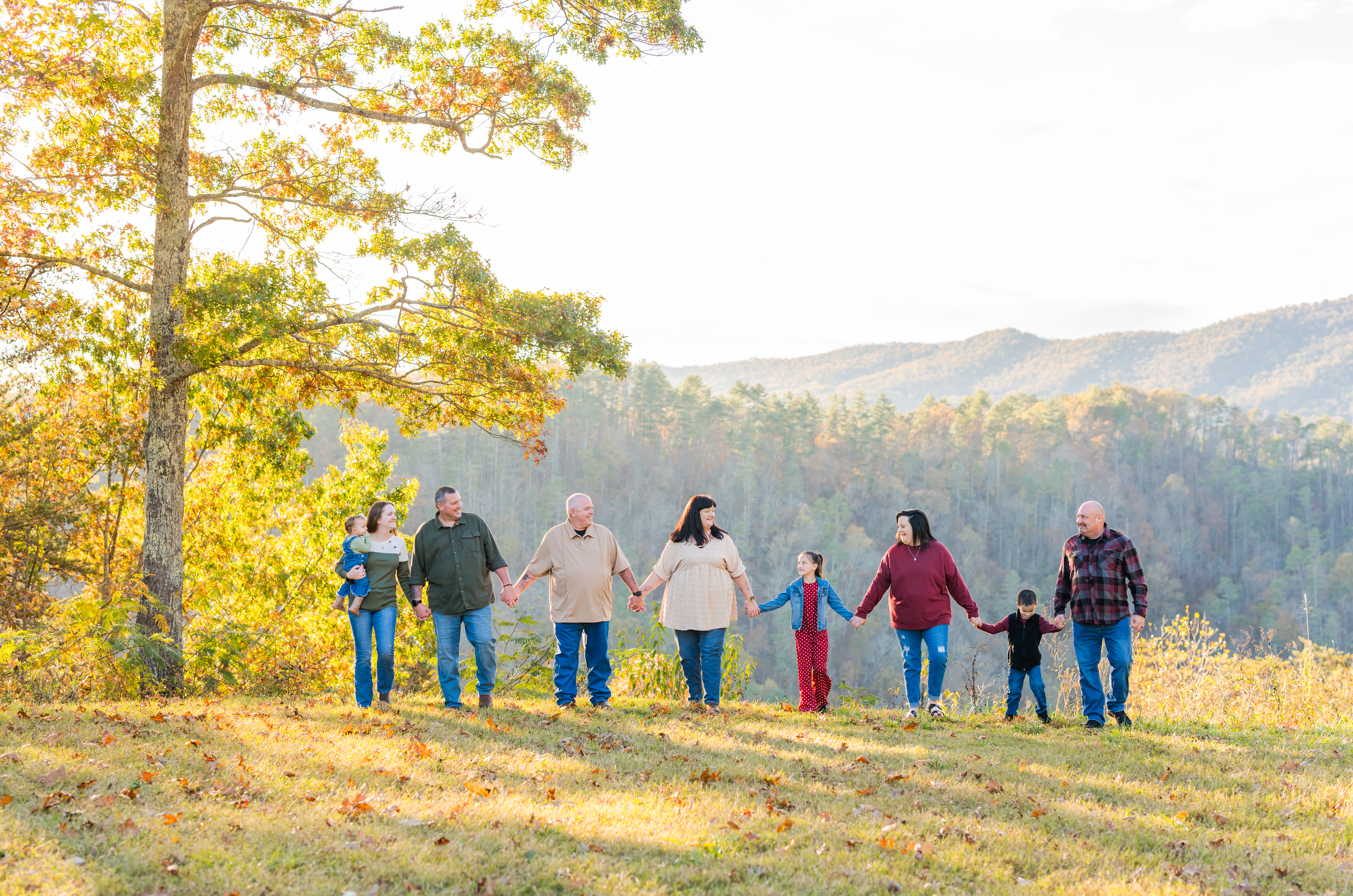 A family holds hands laughing with each other and walking in the national park during their fall family session in gatlinburg