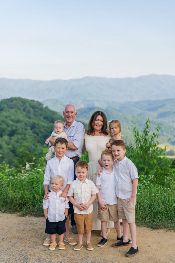 Grandparents and all of their grandchildren together with the mountains behind them while on a family vacation in the great smoky mountains in Gatlinburg, Tennessee