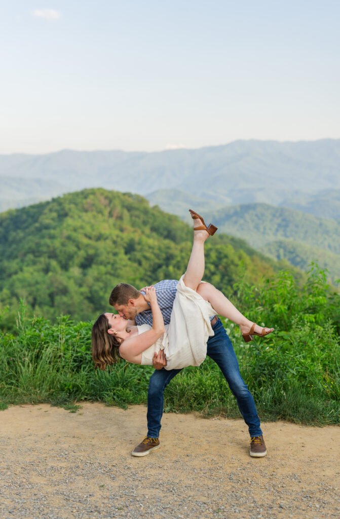 A man holding his wife dipping her during an intimate kiss with a beautiful view of the Smoky Mountains in Gatlinburg