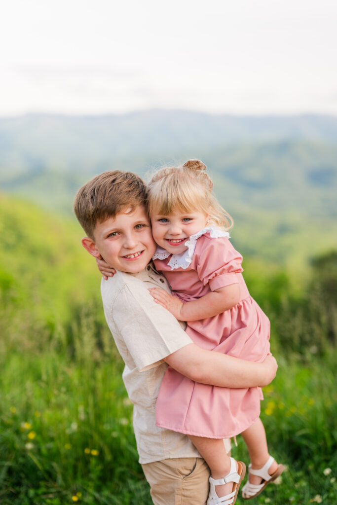 Smoky Mountain family photographer captures young boy hugging his little sister while both smile at the camera in Great Smoky Mountains National Park.