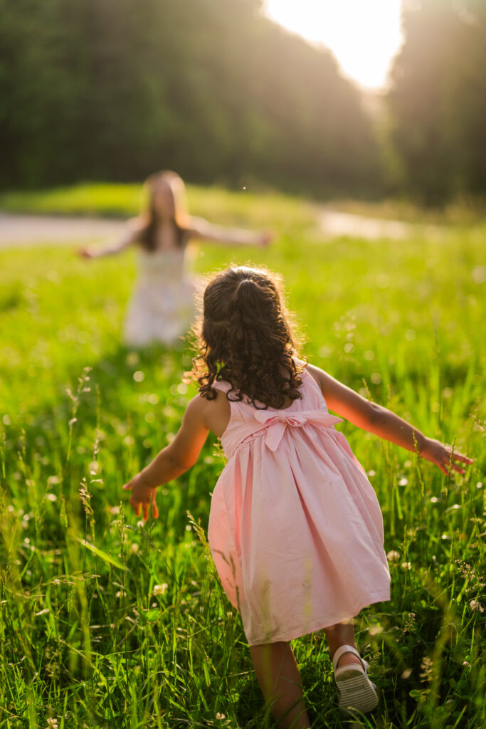 Smoky Mountain family photographer captures young girl running through a field with arms open to hug her mom at sunset in the Smoky Mountains.