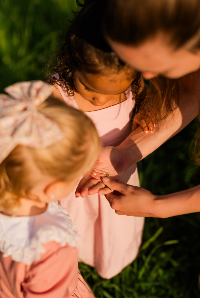 Smoky Mountain family photographer captures mother showing her young daughter and niece a ladybug in her hand during Gatlinburg family photo session.