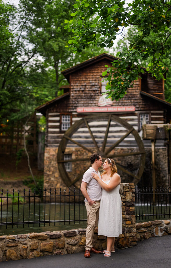 Dollywood engagement session capturing couple kissing in front of iconic Grist Mill in Pigeon Forge, Tennessee