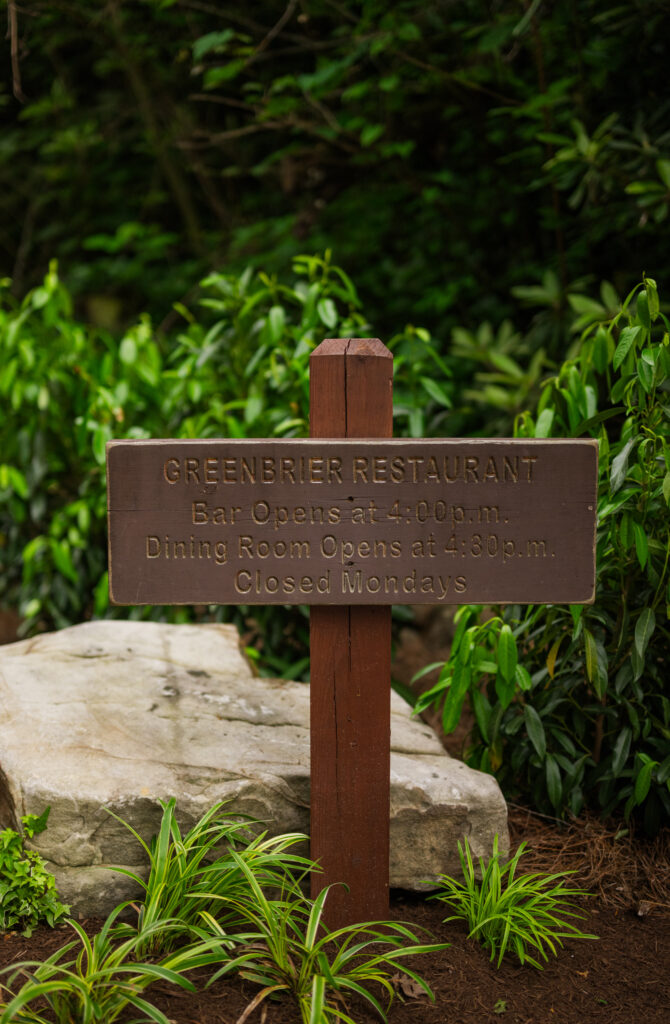 Sign displaying hours of operation for The Greenbrier Restaurant in Gatlinburg, Tennessee, designed like a hiking trail sign in the Smoky Mountains.