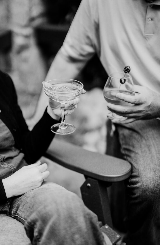 Couple toasting craft cocktails outside by the fire pit at The Greenbrier Restaurant in Gatlinburg, Tennessee, a popular Smoky Mountains dining spot.