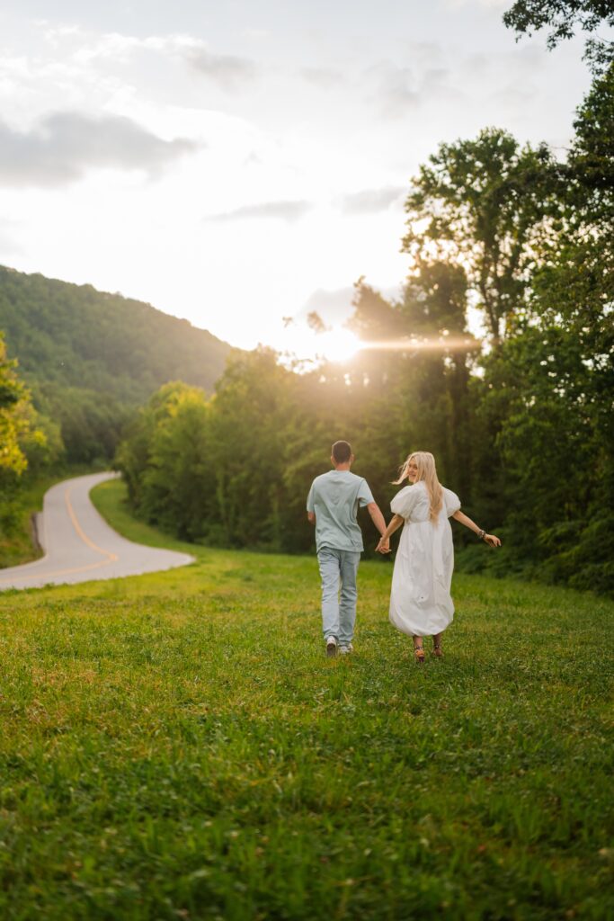 Engaged couple running hand-in-hand into glowing sunset during Smoky Mountains engagement session in Gatlinburg, Tennessee