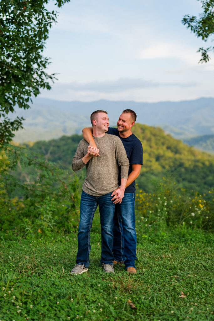 LGBTQ gay couple embracing during engagement session with mountains in the background while on vacation in Gatlinburg, Tennessee