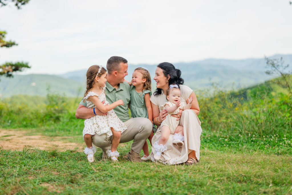 Pigeon Forge photographer captures a family portrait session in the mountains of a small family cuddling up laughing with the mountains in the background
