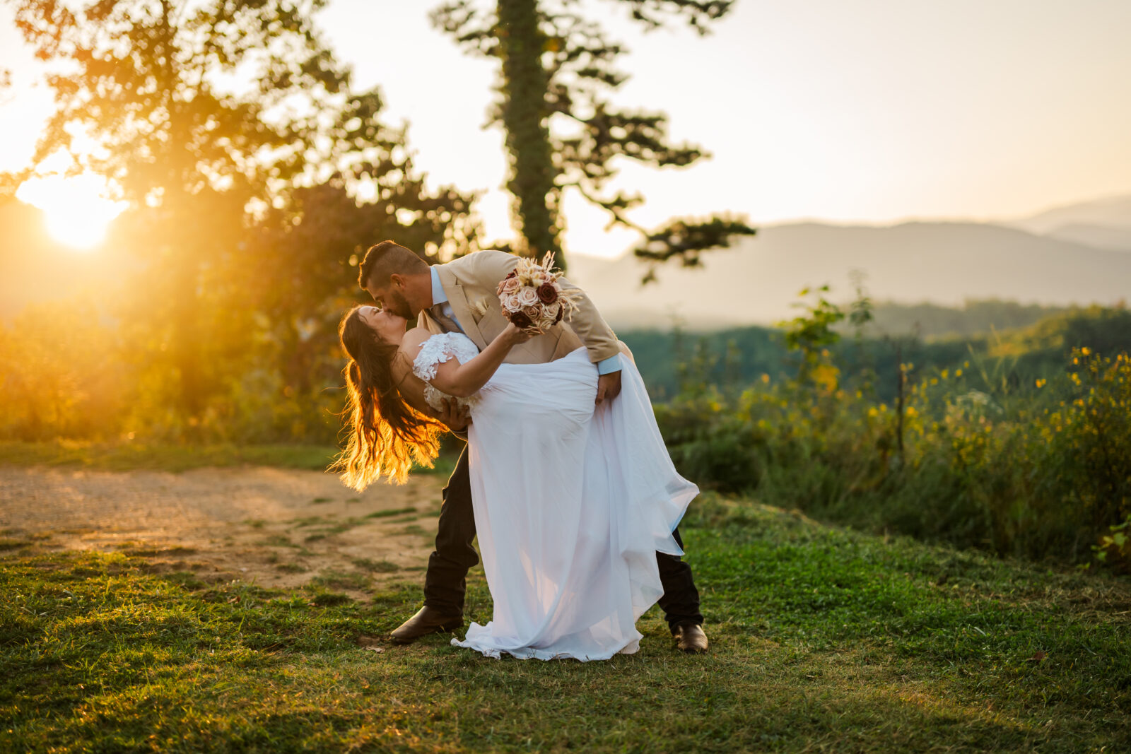 Romantic dip kiss captured at sunrise with glowing golden light in the Smoky Mountains — timeless Gatlinburg wedding photography.