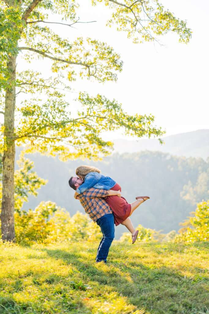 Bride-to-be laughing as her fiancé spins her in front of mountain views.