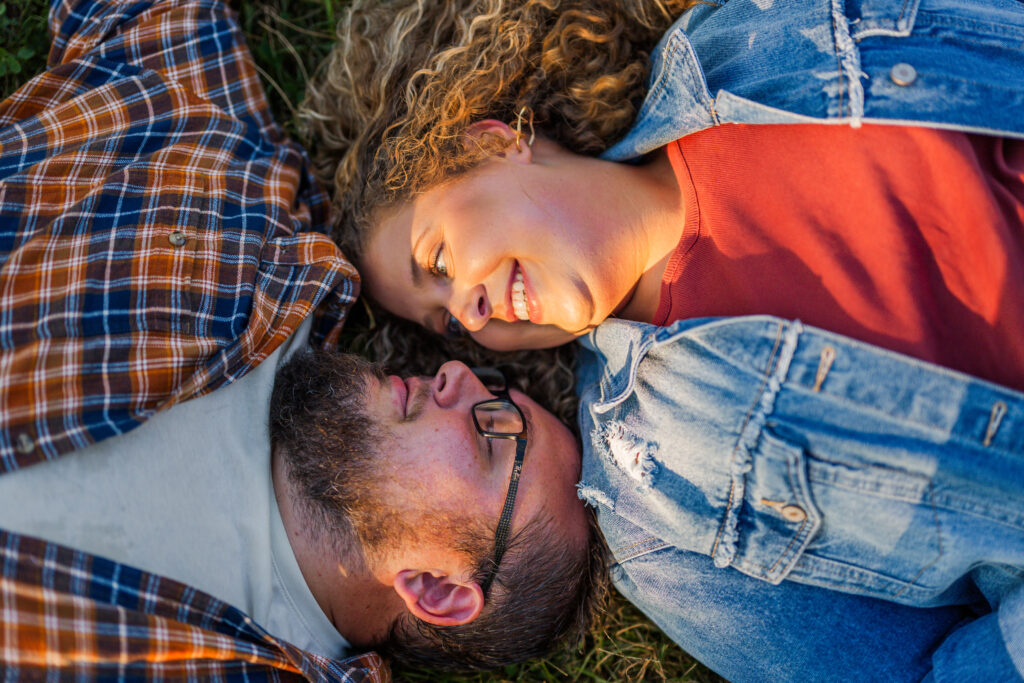 couple laying on the ground smiling at each other in the national park.