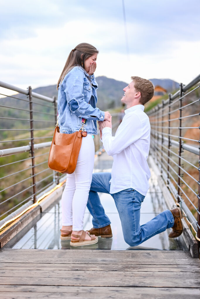 a man proposing to a woman on the glass bottom sky bridge in gatlinburg