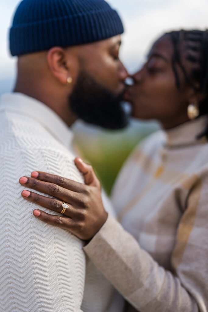 a couple kissing after getting engaged and showing off her engagement ring 