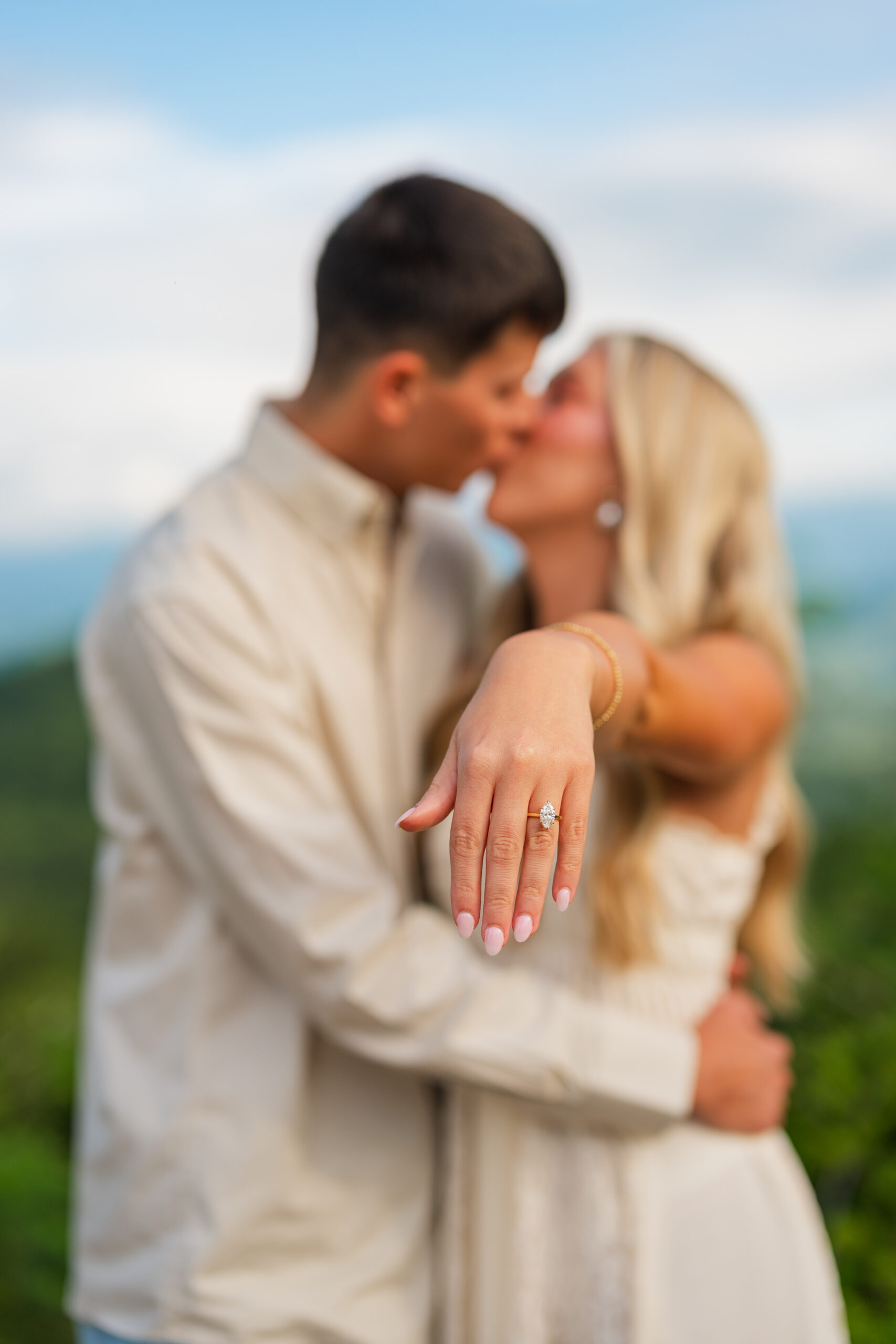 couple kissing sowing off engagement ring