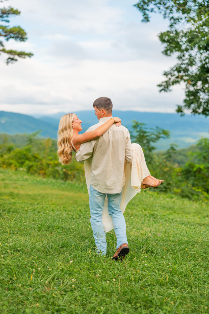 man holding woman walking towards mountains in gatlinburg Tennessee during engagement session